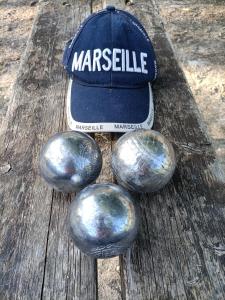 drei Metallkugeln und ein Hut auf einem Holztisch in der Unterkunft Villa du soleil in Les-Pennes-Mirabeau