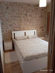 um quarto com uma cama branca e uma parede de pedra em Casa de piedra céntrica. em Ribeira