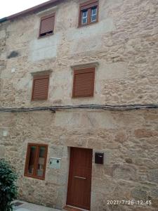 ein Steingebäude mit braunen Türen und Fenstern in der Unterkunft Casa de piedra céntrica. in Ribeira