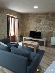 ein Wohnzimmer mit einem blauen Sofa und einem TV in der Unterkunft Casa de piedra céntrica. in Ribeira