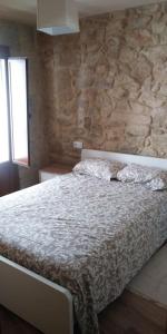 uma cama num quarto com uma parede de pedra em Casa de piedra céntrica. em Ribeira