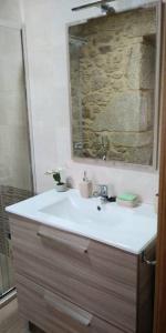 uma casa de banho com um lavatório e um espelho em Casa de piedra céntrica. em Ribeira