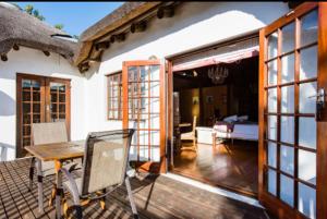 a house with a wooden deck with a table and chairs at Mead, Pinelands in Cape Town
