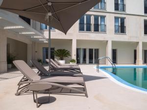 a row of lounge chairs and an umbrella next to a swimming pool at Superior Seaview Apt. with Pool in Umag