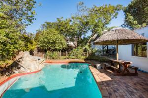 a swimming pool with a picnic table and an umbrella at Mead, Pinelands in Cape Town