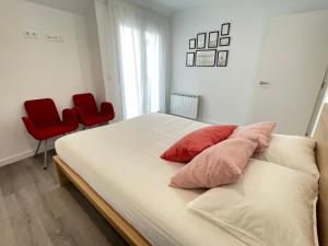 um quarto com uma cama com 2 cadeiras vermelhas em Piso Otero Pedrayo em Vilagarcía de Arousa