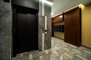 a bathroom with a black door and a tile floor at Harizma apartmani - Maja in Kragujevac