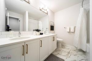 La salle de bains blanche est pourvue d'un lavabo et de toilettes. dans l'établissement Boho Luxe Home, Sleeps 12, AirCon, King Bed, WiFi, à Edmonton