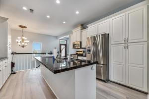 cocina con armarios blancos y encimera negra en Beach Stunner en Galveston