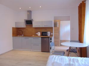 a kitchen with white cabinets and a table and a table and chairs at Apartamenty Monik Świętochłowice in Świętochłowice