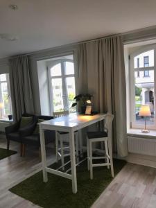 a white table and chairs in a room with windows at Lilla Drottninggatan Apartment Hotel in Helsingborg
