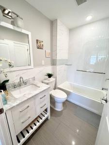 a white bathroom with a sink and a toilet and a tub at 302 Comfy Cabin 1BD with city view in Center city in Philadelphia +43 photos