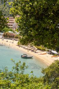 un barco en el agua junto a una playa en Cape Blue Suites, en Achladies