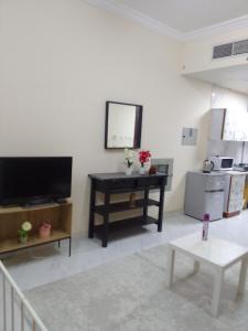 sala de estar con TV de pantalla plana y mesa en استوديو مفروش en Sharjah