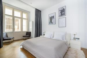 a white bedroom with a bed and two chairs at Elegant Paris Ave apartment with a Terrace in Prague