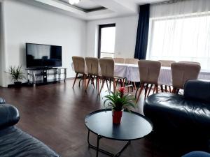 een woonkamer met een tafel en stoelen en een televisie bij Alpha Pool House in Ghionea