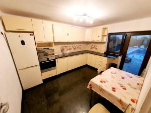 a kitchen with white cabinets and a table and a refrigerator at Alpha Pool House in Ghionea