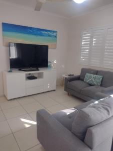 sala de estar con sofá y TV de pantalla plana en Ocean Breeze Apartments, en Hervey Bay