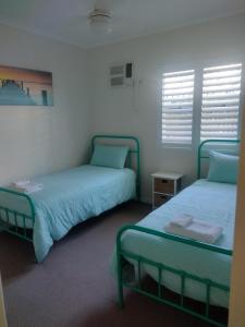 2 camas en una habitación con sábanas y almohadas azules en Ocean Breeze Apartments, en Hervey Bay