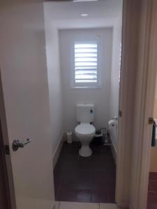 een badkamer met een toilet en een raam bij Ocean Breeze Apartments in Hervey Bay