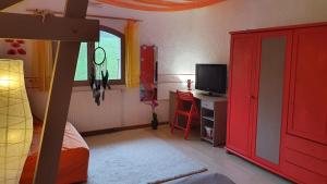 a bedroom with a bed and a tv and a red cabinet at Le lacustre in Choisy