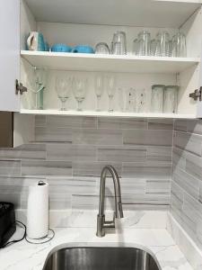 a kitchen with a sink and wine glasses on a shelf at 305 Cozy and lovely 1BDR apartment in Center City in Philadelphia