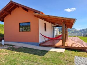 a small house with a hammock on a deck at Chalés Conforto Mineiro in Gonçalves
