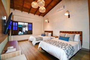 a bedroom with two beds and a flat screen tv at Hotel Salento Real Eje Cafetero in Salento