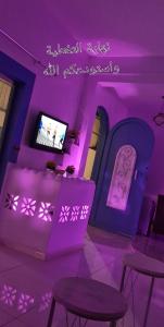 a room with purple lighting and tables and a tv at شاليهات ليله الدرب in Qarār