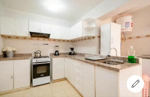 a white kitchen with a stove and a sink at Habitación con baño compartido Miraflores Larcomar in Lima