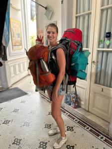 una mujer parada frente a una puerta con su mochila en Reina Madre Hostel en Buenos Aires