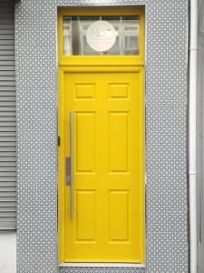 une porte jaune sur un bâtiment avec un panneau sur celui-ci dans l'établissement No.5, à Derry Londonderry