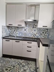 uma cozinha com armários brancos e uma parede de azulejos em Loft a 30 metri dalla Spiaggia em LʼAnnunziata