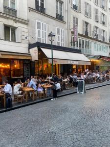 um grupo de pessoas sentadas em mesas fora de um restaurante em Appartement Paris rue Montorgueil em Paris