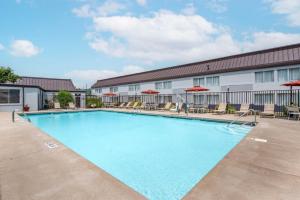 a pool in front of a hotel with chairs and umbrellas at Best Western Plus Bridgeport Inn in Bridgeport