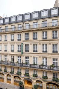 パリにあるオテル オルセ オペラ ベスト ウェスタン プレミア コレクションの窓とバルコニーが備わる大きな建物です。