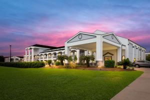 a large building with a green lawn in front of it at Best Western La Place Inn in Laplace
