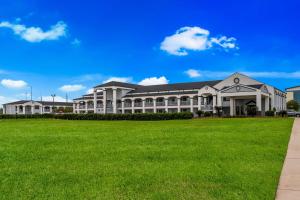 a large building with a green lawn in front of it at Best Western La Place Inn in Laplace