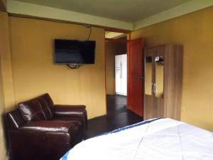 1 dormitorio con sofá, silla y TV en Casa Machupicchu - Huayllabamba, Urubamba Cusco, Perú, 