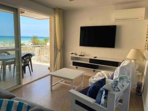 ein Wohnzimmer mit einem Sofa, einem TV und einem Tisch in der Unterkunft Vacaciones Canet Playa - en primera linea in Canet d'en Berenguer