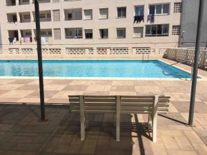 a bench sitting in front of a swimming pool at Vacaciones Canet Playa - en primera linea in Canet de Berenguer