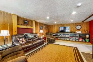 a living room with a leather couch and a tv at Hibernation Station at Big Pine Retreat in Crescent