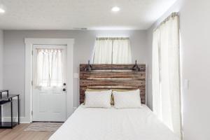 1 dormitorio con cama blanca y cabecero de madera en Greenwood Getaway Apartment en Greenwood