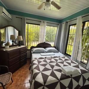 Schlafzimmer mit einem Bett, einem Spiegel und Fenstern in der Unterkunft La Esmeralda Villa in Orotina