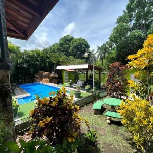 einen Garten mit einem Pool, einem Tisch und Stühlen in der Unterkunft La Esmeralda Villa in Orotina