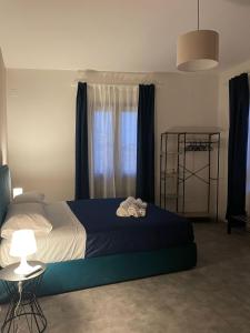 a bedroom with a bed with a blue blanket and a window at Dimora 7 fontane in Paola