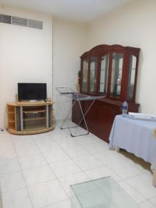 a living room with a tv and a table with a table at شقه غرفتين مفروشه in Sharjah