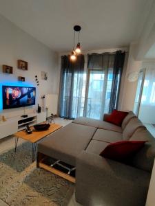 uma sala de estar com um sofá e uma televisão de ecrã plano em Antonia's cozy apartment em Agia Triada