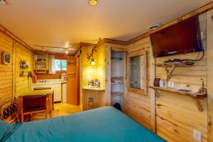 a bedroom in a log cabin with a bed and a kitchen at Cedaredge Lodge, Cabin 3 in Cedaredge