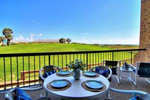 a table and chairs on a balcony with a view of a field at Aransas Princess 112 in Port Aransas